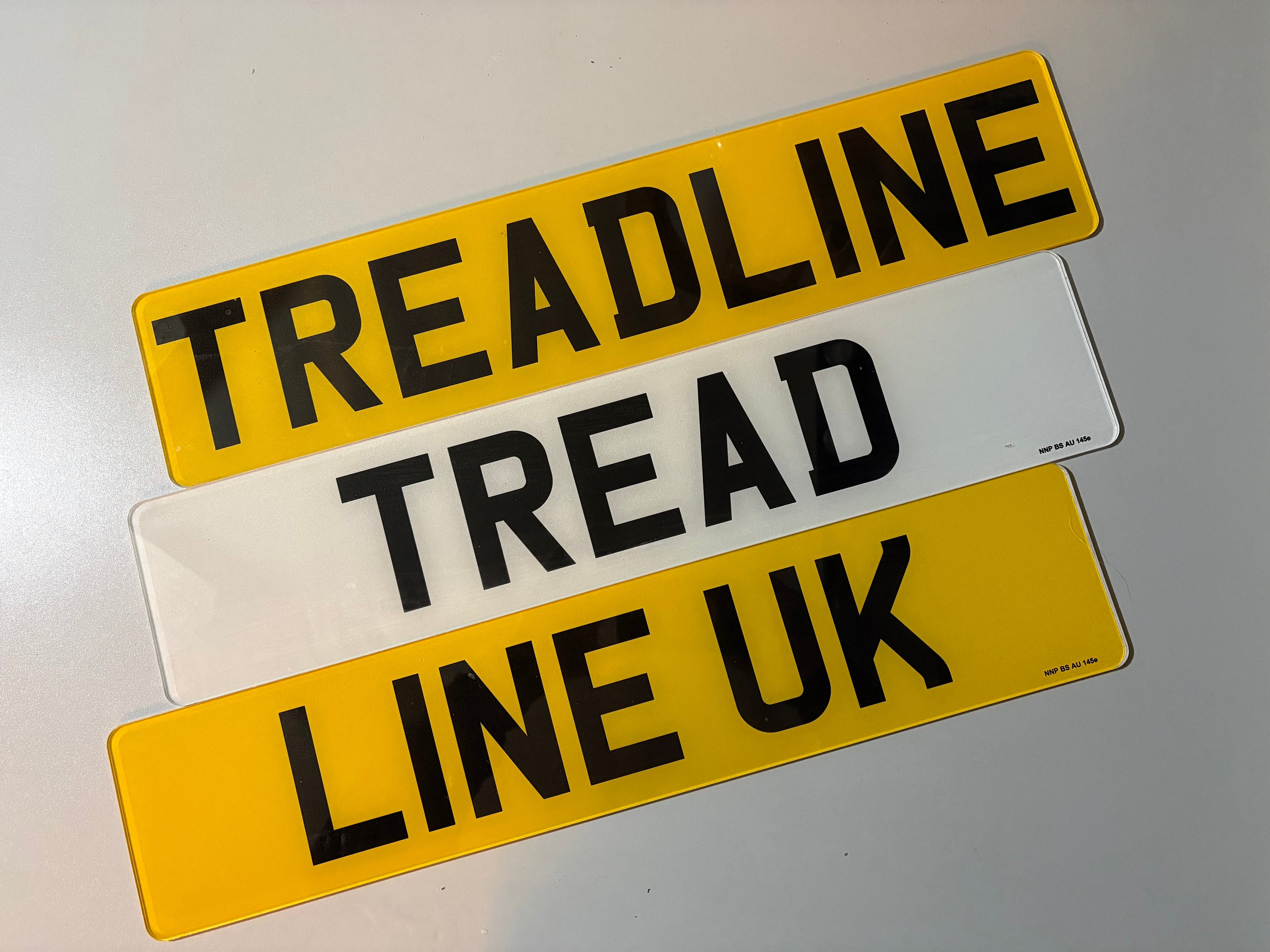 Three license plate-style signs with text on a gray background